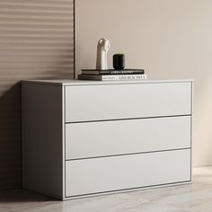 a white chest of drawers with books on top