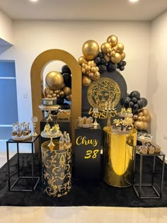 a table topped with black and gold decorations next to two vases filled with balloons