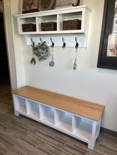 a wooden bench sitting in front of a wall with hooks on it's sides