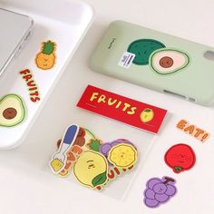 two cell phones sitting next to each other on top of a white table with fruit stickers