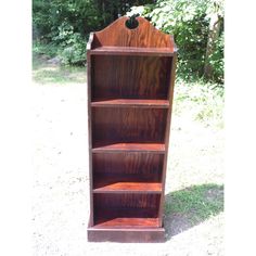 a wooden bookcase sitting on top of a grass covered field