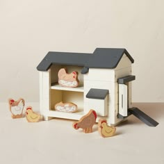 a toy house with chickens and other toys in front of it on a white surface