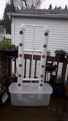 a white plastic chair sitting on top of a wooden deck next to a planter