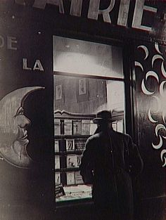 an old photo of a man standing in front of a store window with his back to the camera