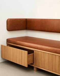 a brown leather bench sitting on top of a wooden shelf next to a white wall