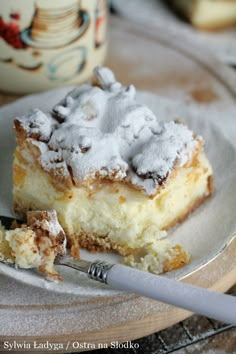 a piece of cake sitting on top of a white plate next to a cup of coffee