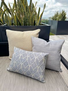 four pillows sitting on top of a wooden table next to a planter filled with succulents