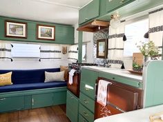 a kitchen with green cabinets and white counter tops next to a blue couch in front of a window