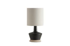 a black table lamp with a white shade on the base and a beige drum light