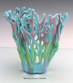 a blue and green vase sitting on top of a white table next to a pink wall