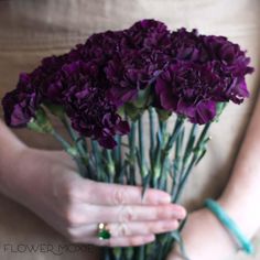 a woman holding purple flowers in her hands