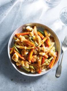 a bowl filled with pasta and vegetables next to a glass of wine on a table