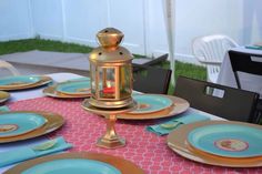 a table set with plates, silverware and a lantern on top of the table