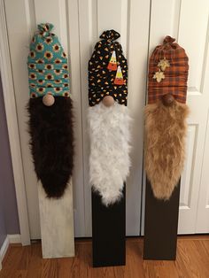 three wooden skis decorated to look like santa's hats and beards are hanging on the door