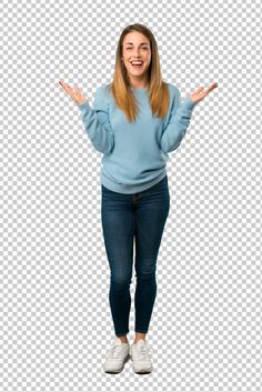 a woman standing with her hands out in front of her face, wearing blue sweater and jeans