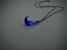 a blue necklace with an upside down crescent shaped pendant hanging from it's side