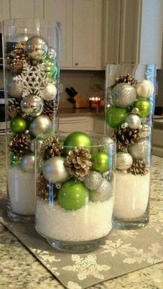 three glass vases filled with ornaments on top of a kitchen counter covered in snow