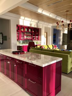 a large kitchen island in the middle of a living room with two green couches