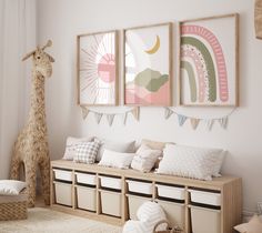 a room with two giraffes and three pictures on the wall above it