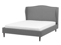 a bed with a gray upholstered headboard and white sheets on the bottom