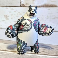 a white and black bear with skulls on it's back, sitting on a wooden surface