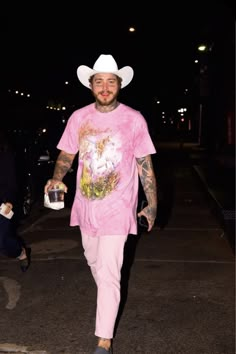 a man in a pink shirt and hat walking down the street