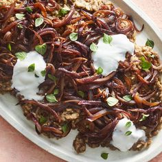 a white plate topped with meat and rice covered in sour cream on top of a table