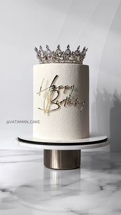 a white and gold birthday cake with a crown on top