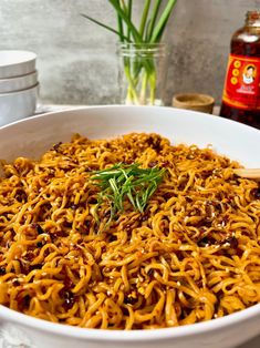 a white bowl filled with noodles and garnished with herbs