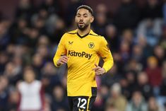 a soccer player in yellow and black uniform on the field with spectators watching him from behind