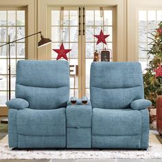 two blue recliners sitting next to each other in front of a christmas tree