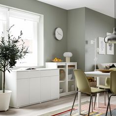 a dining room table and chairs with a clock on the wall behind them in front of a window