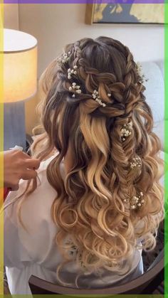 a woman is getting her hair done with flowers in her hair and sitting on a chair