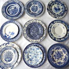 many blue and white plates are arranged on a tablecloth with one plate in the middle