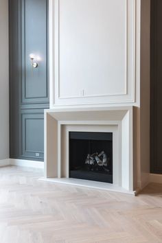 an empty room with a fireplace in the center and white cabinets on either side, along with parquet flooring