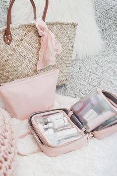 an open pink purse sitting on top of a white rug next to a handbag