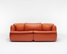 an orange leather couch sitting on top of a white floor