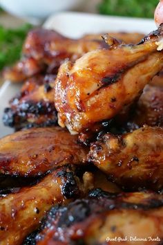 grilled chicken wings on a white plate with broccoli in the back ground