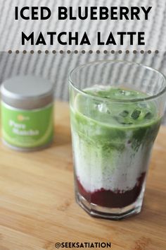 an iced blueberry matcha latte in a glass on top of a wooden table