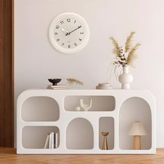 there is a clock on the wall next to a shelf with books and vases