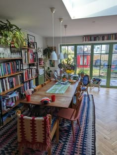 a dining room table with chairs and bookshelves in front of large glass doors