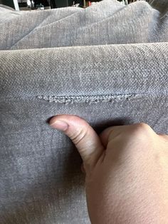 a person pointing to the left side of a couch with their hand on it's pillow