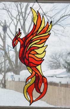 a stained glass window with a red and yellow bird hanging from it's side