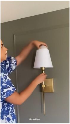 a young boy is trying to fix a light fixture on the wall in his bedroom