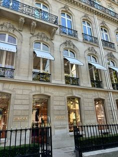 a large building with many windows and balconies on the front, next to a black fence