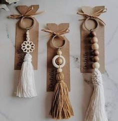 three key chains with tassels hanging from them on top of a marble counter