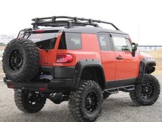 an orange four door jeep parked in a parking lot