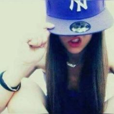 a woman with long hair wearing a new york yankees hat and posing for the camera