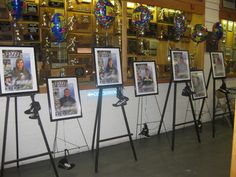 many pictures are hanging on easels in front of a wall with balloons and photos