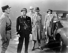 an old black and white photo of men in hats standing next to a vintage car